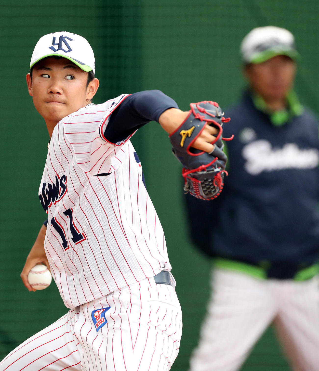 ブルペンで投げ込む奥川。後方は高津監督（撮影・狩俣裕三）