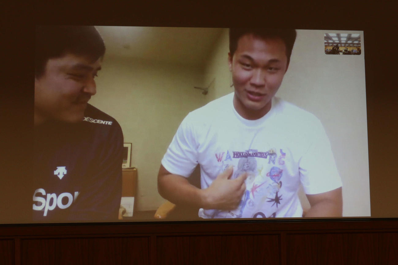 オンライン取材でファンがデザインしたTシャツを披露する日本ハム王柏融（右）。左は林庭逸通訳