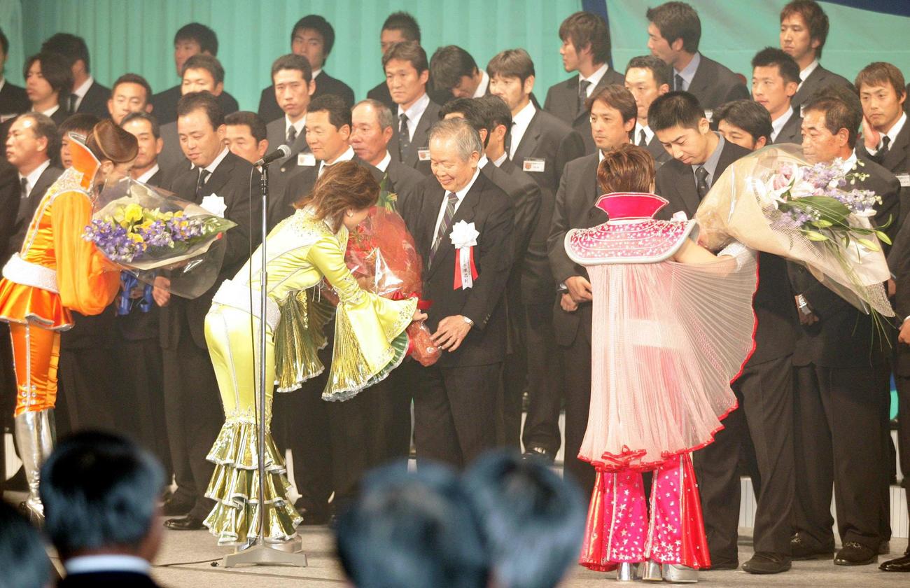 2005セ・リーグ優勝祝賀会　優勝祝賀会で劇団四季の出演メンバーから花束を受け取る左から岡田彰布監督、阪神・手塚昌利オーナー、今岡誠（撮影・栗木一考）