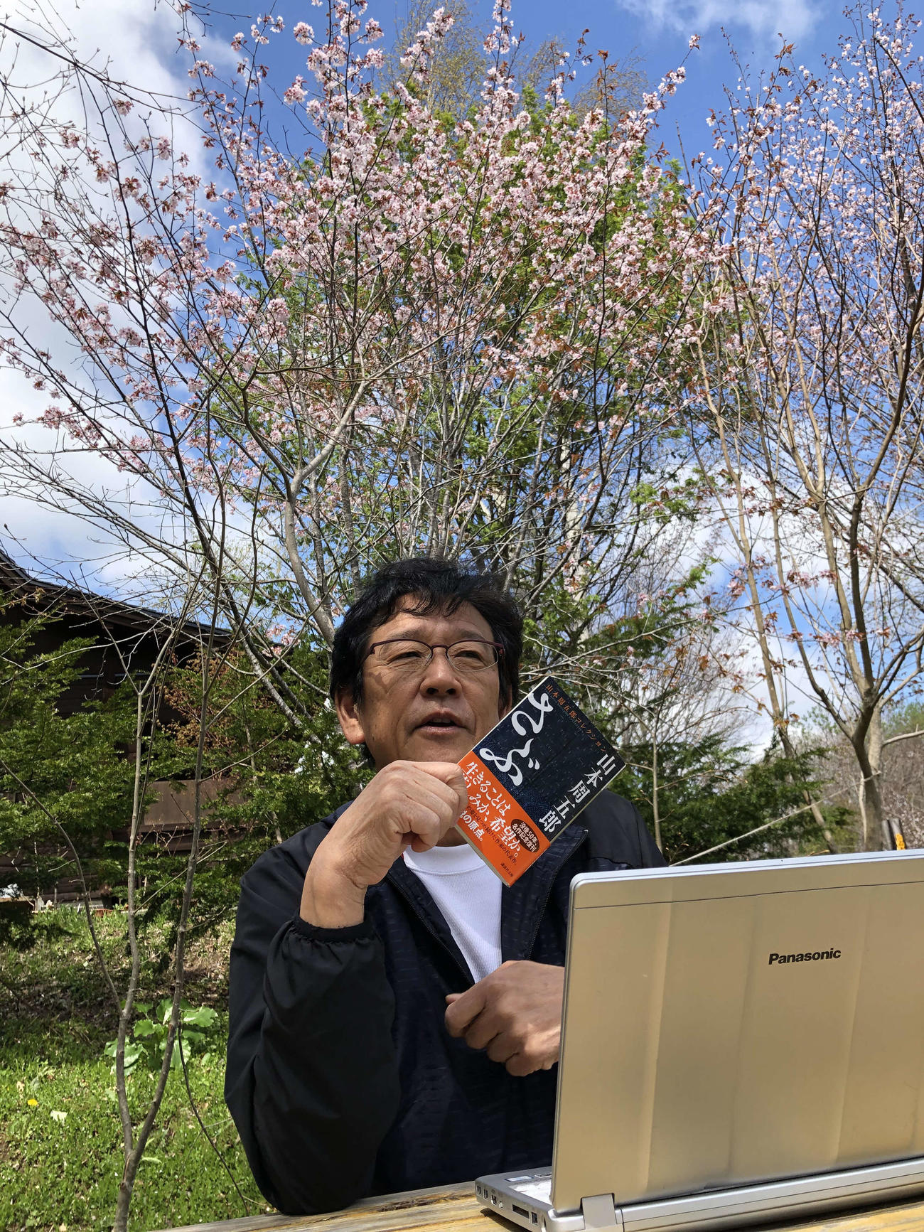 栗山町の「栗の樹ファーム」で満開となった桜をバックに山本周五郎の小説「さぶ」を紹介する日本ハム栗山監督（球団提供）