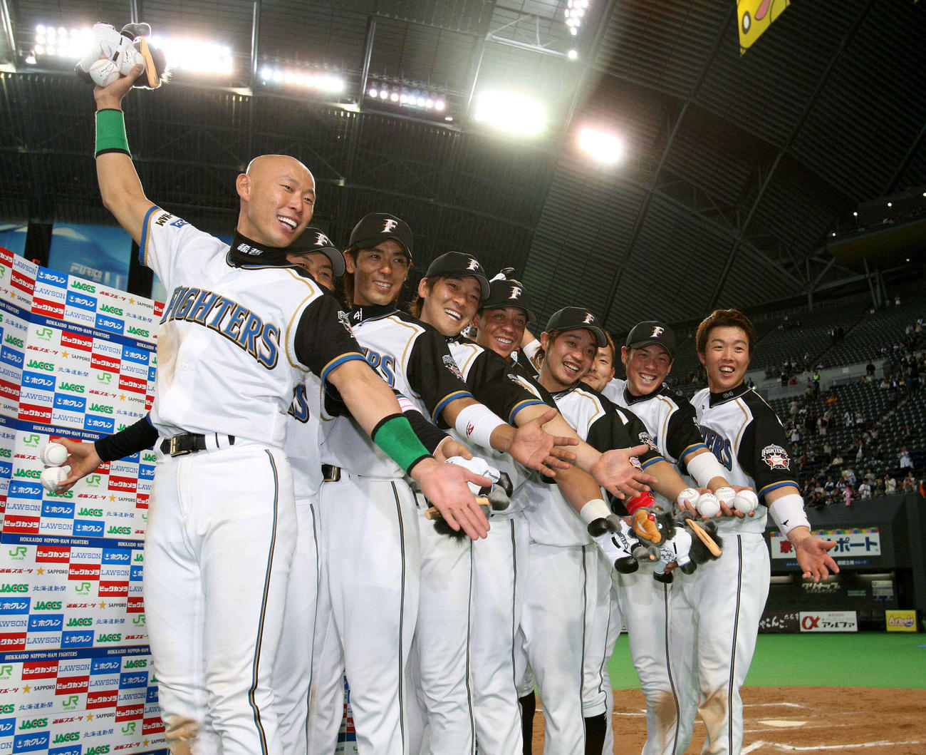 ヒーローインタビュー後、ポーズをつくる日本ハムの9選手（左から森本稀哲、田中賢介、稲葉篤紀、高橋信二、ターメル・スレッジ、小谷野栄一、工藤隆人、高口隆行、鶴岡慎也）（2008年4月8日撮影）