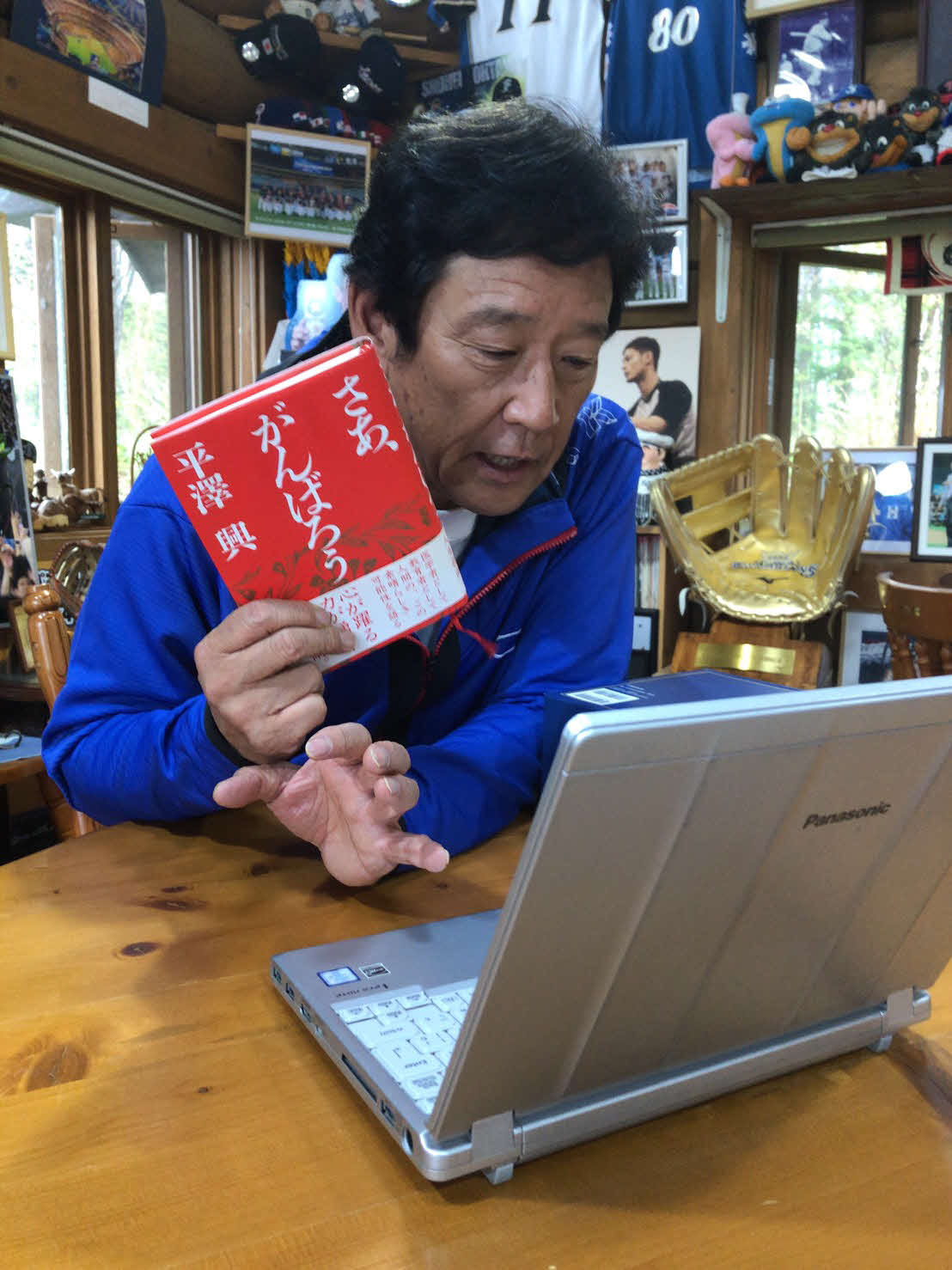 栗山町の「栗の樹ファーム」でオンライン取材を受け、平沢興著「さあ、がんばろう」を紹介する日本ハム栗山監督（球団提供）