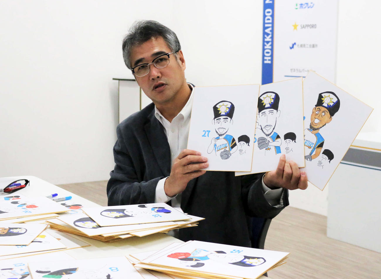 作成中の似顔絵を披露する日本ハム木田投手コーチ