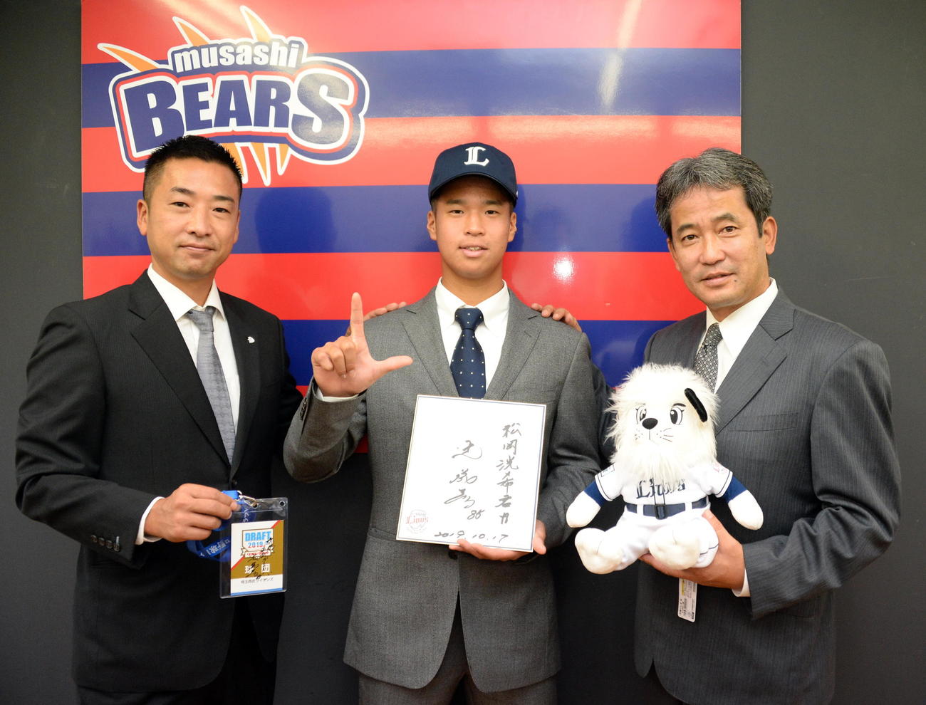 ドラフト後の指名あいさつ。西武3位のBC武蔵・松岡（中央）は、潮崎ディレクター（右）鈴木スカウトからあいさつを受け笑顔でLポーズ（撮影・鈴木正章）