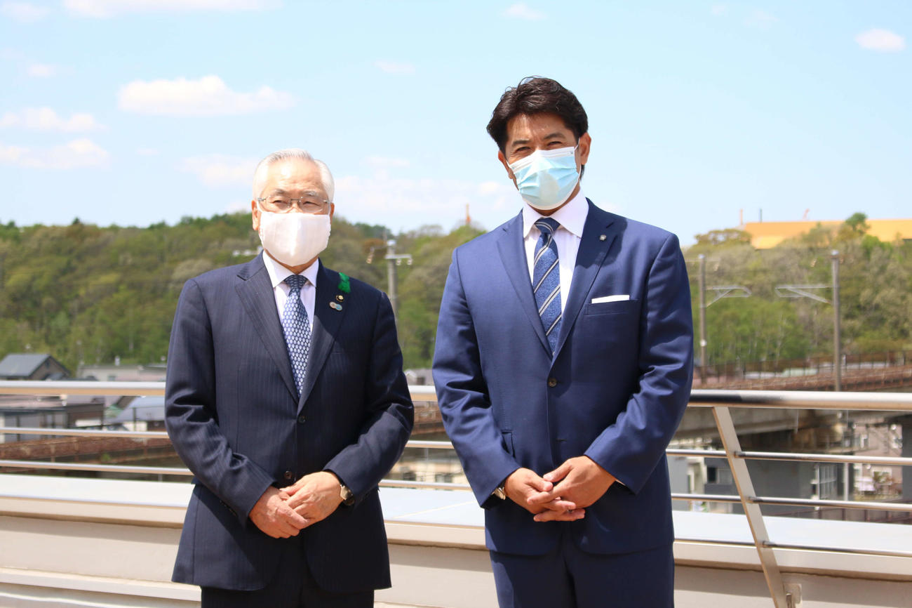 北広島市役所5階テラスで記念撮影する日本ハム稲葉SCOと同市の上野市長（左、後方が「エスコンフィールド北海道」建設地）（撮影・木下大輔）