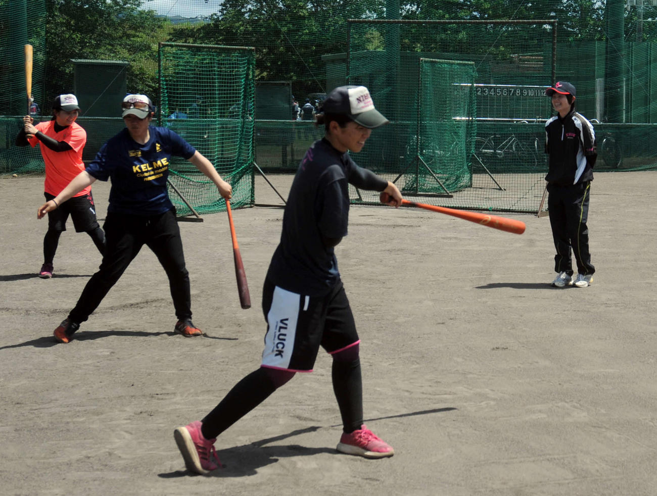 自主練習をする選手たちを見守る坪内監督（右奥）