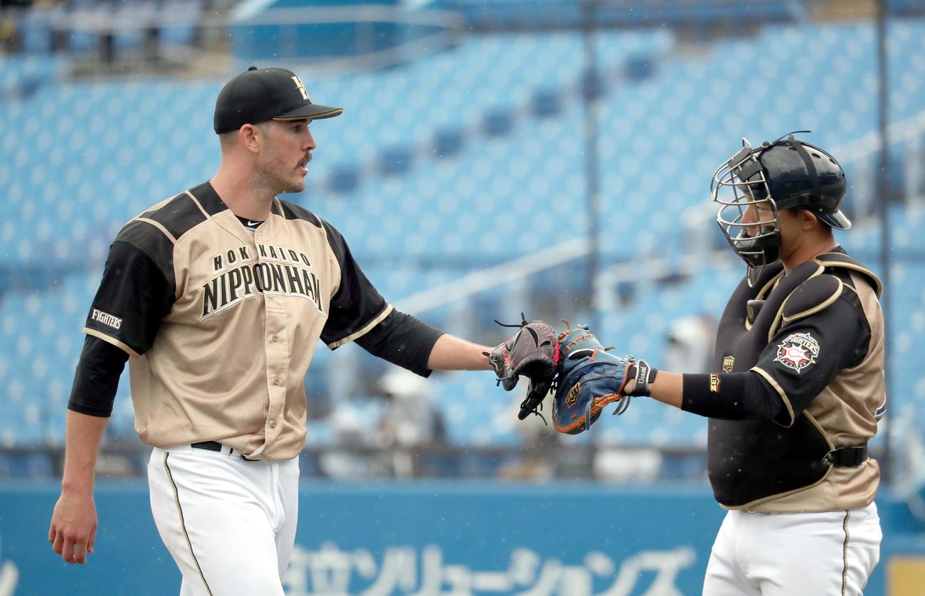 ヤクルト対日本ハム　グラブでタッチしながらベンチに戻る日本ハム・バーヘイゲン（左）と宇佐見（撮影・佐藤翔太）