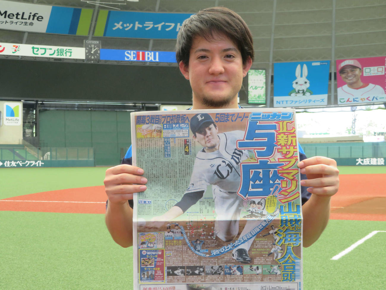 自らが1面に載った日刊スポーツを手に笑顔をみせる西武与座（球団提供）
