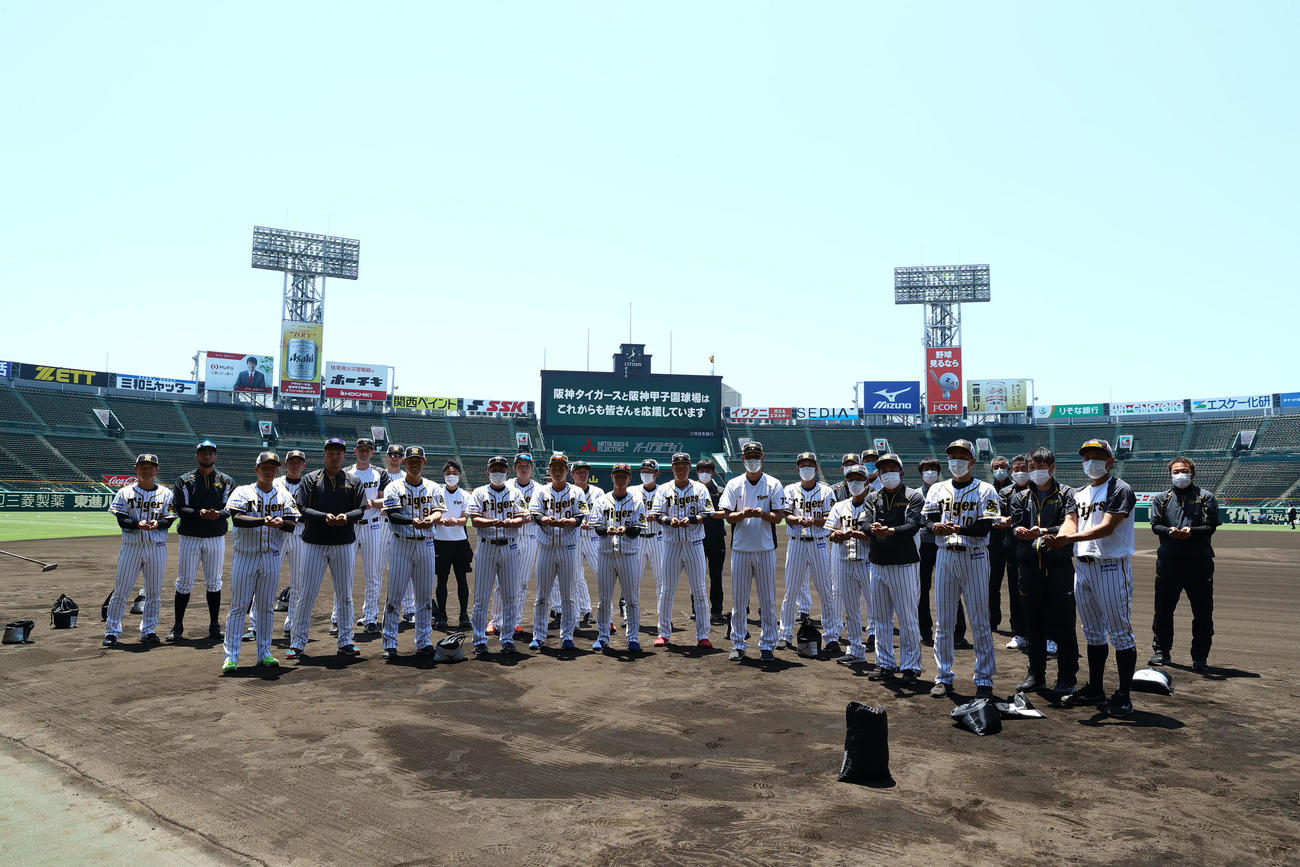 阪神球団提供　甲子園の土を集めるナインと首脳陣（球団提供）