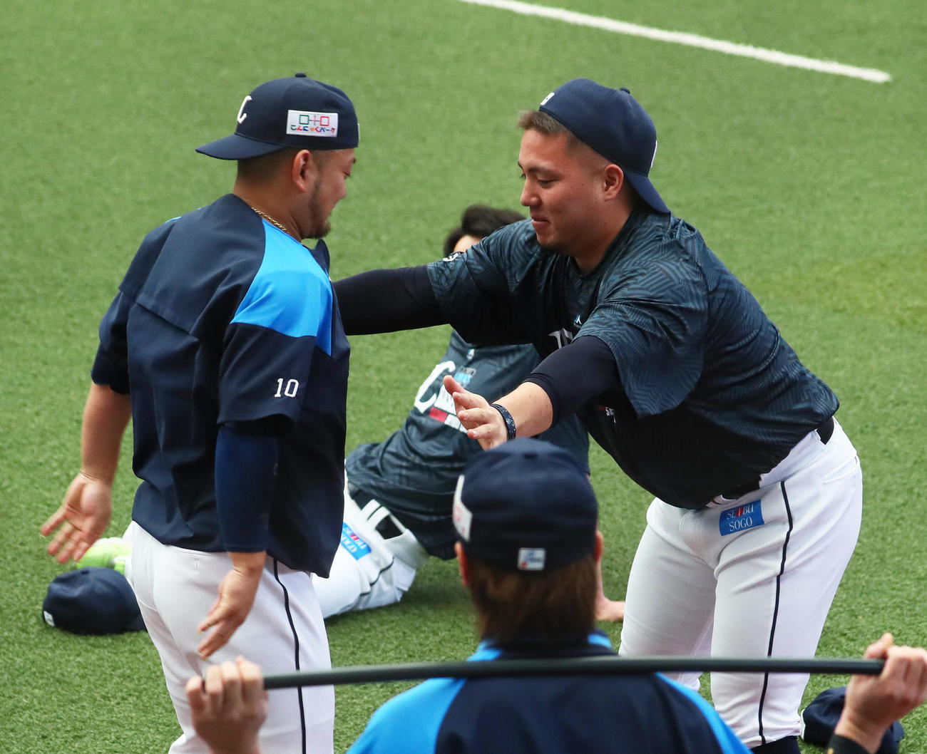 練習前、手押し相撲を楽しむ西武の森（左）と山川（撮影・足立雅史）
