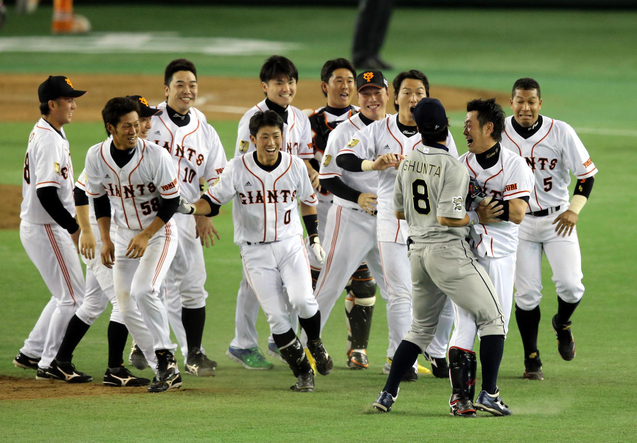 サヨナラの中前打を放ち、ナインから追いかけられる巨人亀井（手前右）はオリックス駿太と激突（13年5月25日）