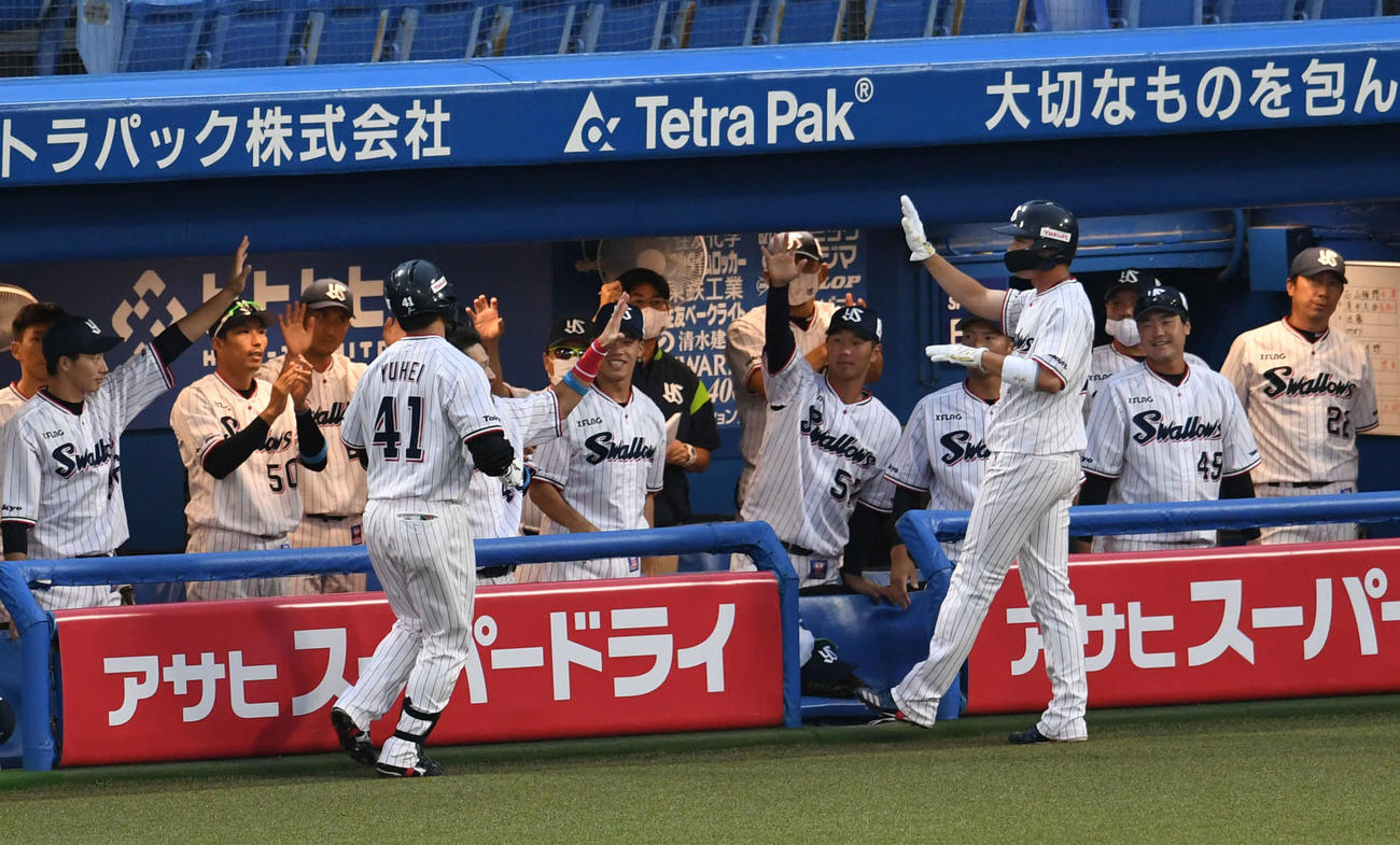 ヤクルト対阪神　1回裏ヤクルト1死二、三塁、雄平（手前左）の犠飛で生還した山田哲（同右）はチームメートとエアタッチ（撮影・山崎安昭）