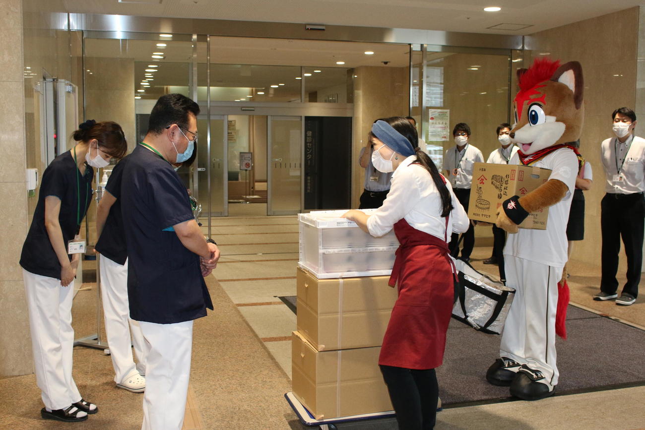 オーガニック弁当を手がける「OrganicKitchenChikyu」の石田香織さん（左から3人目）とともに札幌厚生病院へ弁当を届ける日本ハムのマスコット・フレップ（撮影・木下大輔）