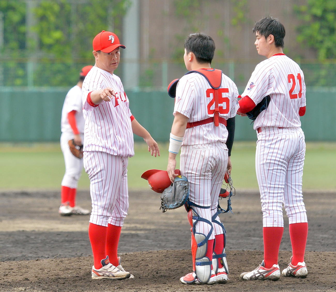 マウンドでバッテリーに言葉をかける富士大・豊田監督（左端）