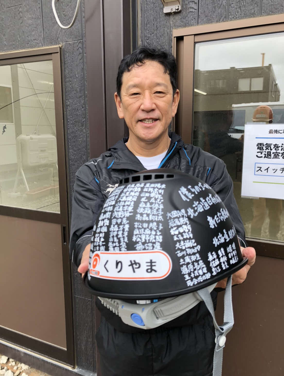 北広島の新球場建設予定地で建設作業に従事する作業員からメッセージ入りのヘルメットを贈られて笑顔の日本ハム栗山監督（球団提供）