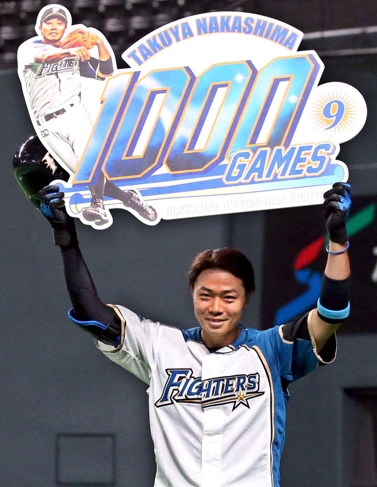 通算1000試合出場を達成し、記念ボードを掲げる日本ハム中島（撮影・黒川智章）