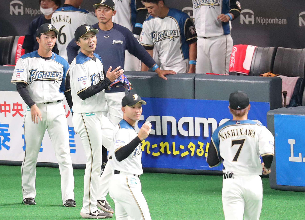 ベンチ前で日本ハム西川（右手前）を迎える上沢（左から2人目）（撮影・佐藤翔太）