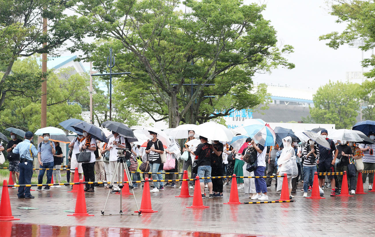 雨の中、巨人－ヤクルト戦の開場を待つ観客ら（撮影・前田充）