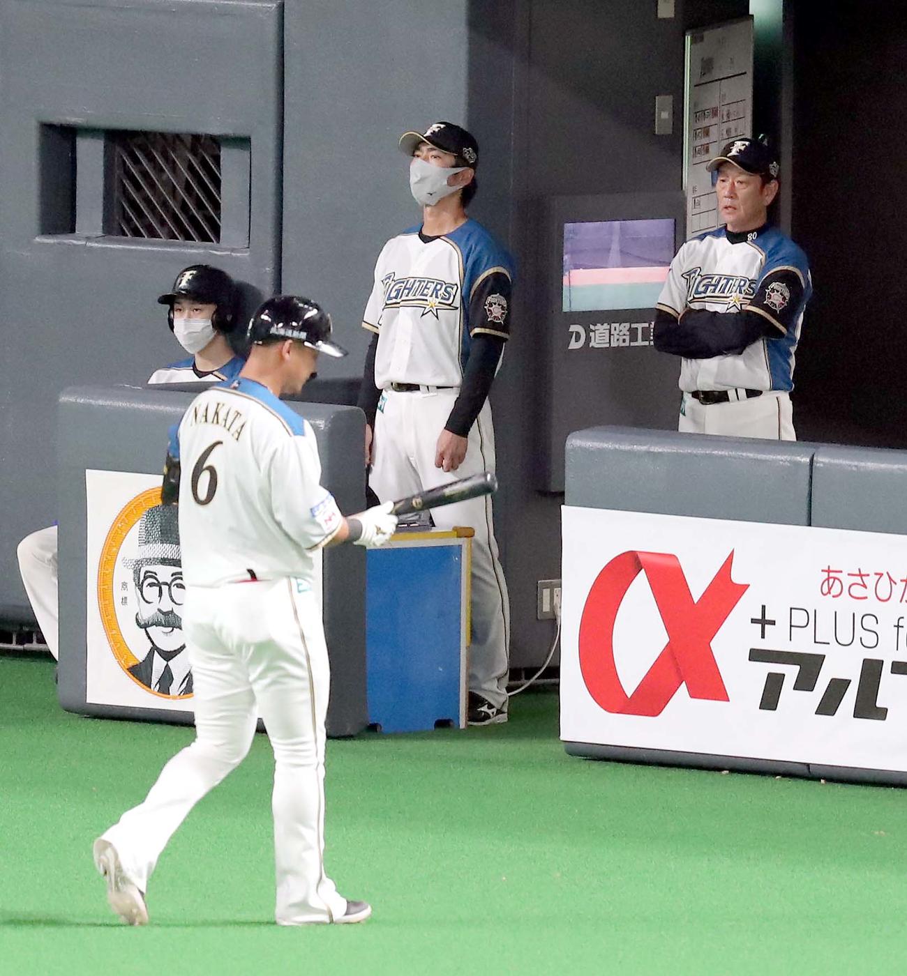 日本ハム対ロッテ　ベンチで険しい表情の日本ハム栗山監督（右奥）。左手前は一邪飛に終わりベンチに戻る中田（撮影・佐藤翔太）