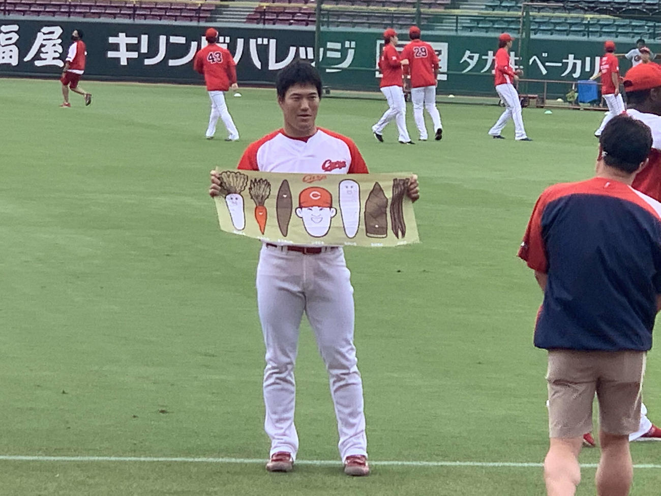 似顔絵が描かれた「カープ手拭い（八百屋磯村）」を手に持ちアピールする広島磯村（撮影・古財稜明）