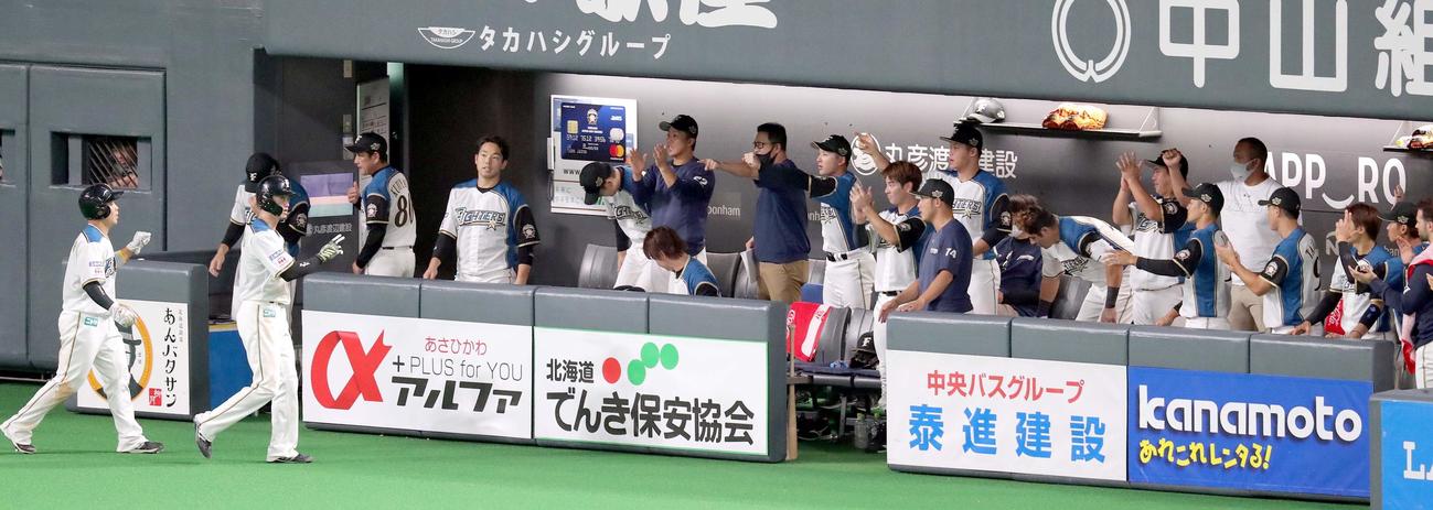 日本ハム対ロッテ　1回裏日本ハム1死二、三塁、中田の中前適時打で生還した西川（左から2人目）と近藤はチームメートに出迎えられる（撮影・佐藤翔太）