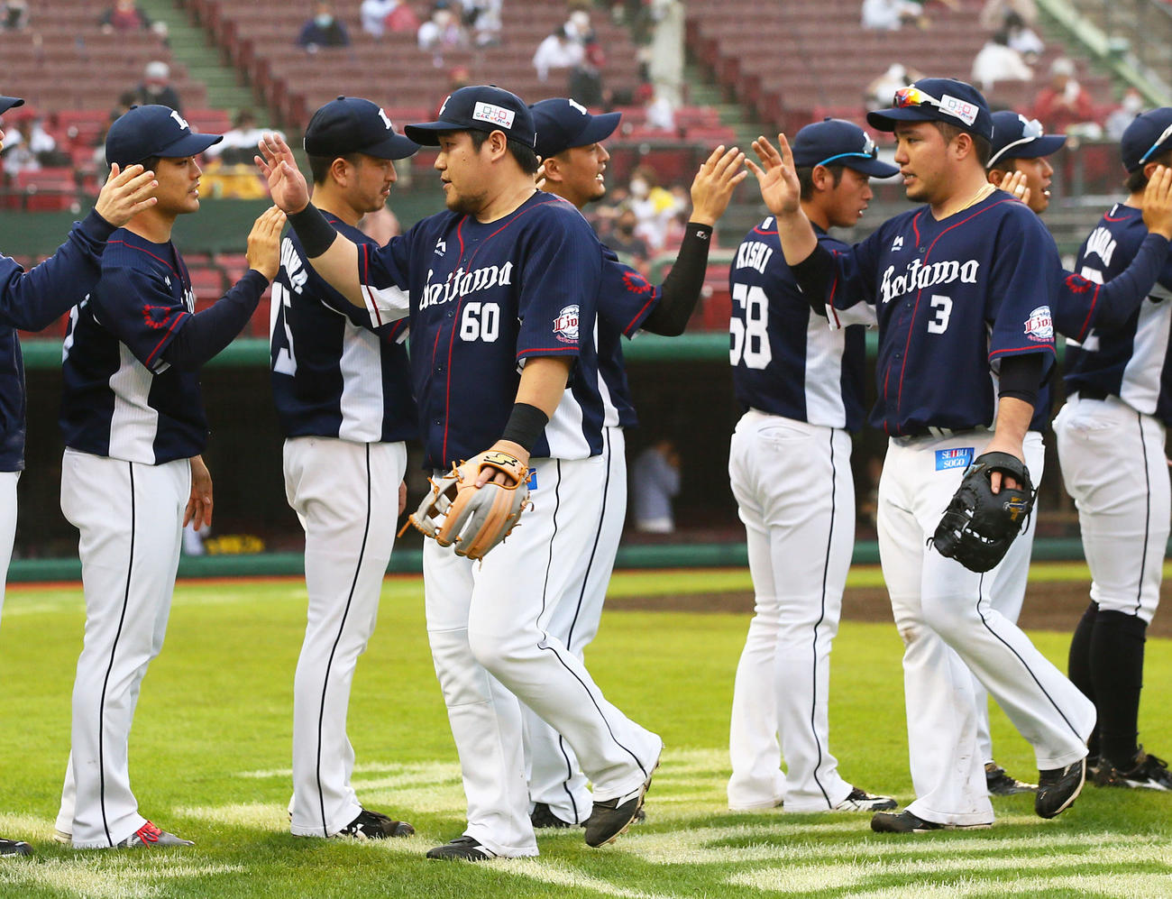 楽天対西武　勝利しナインとエアタッチを交わす西武の中村（左）と山川（右）。左端は勝利投手の松本（撮影・足立雅史）