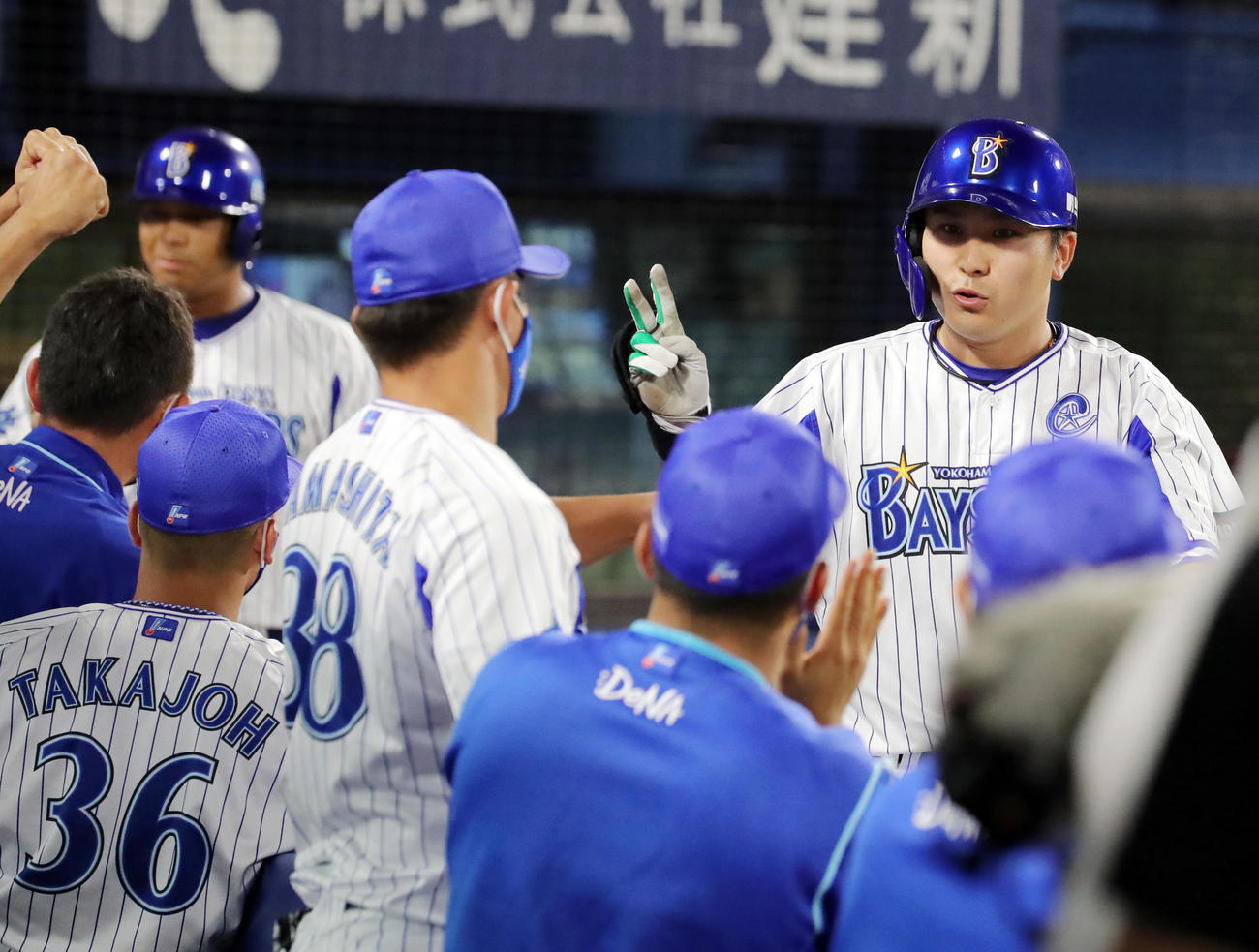 DeNA対ヤクルト　7回裏DeNA無死一塁、左越え2点本塁打を放ち指を2本立ててナインの出迎えを受ける佐野（撮影・垰建太）