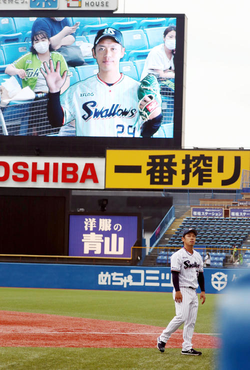 ヤクルト対巨人 大型スクリーンに映し出される自身の静止画を背にウオーミングアップをする小川(撮影・狩俣裕三)