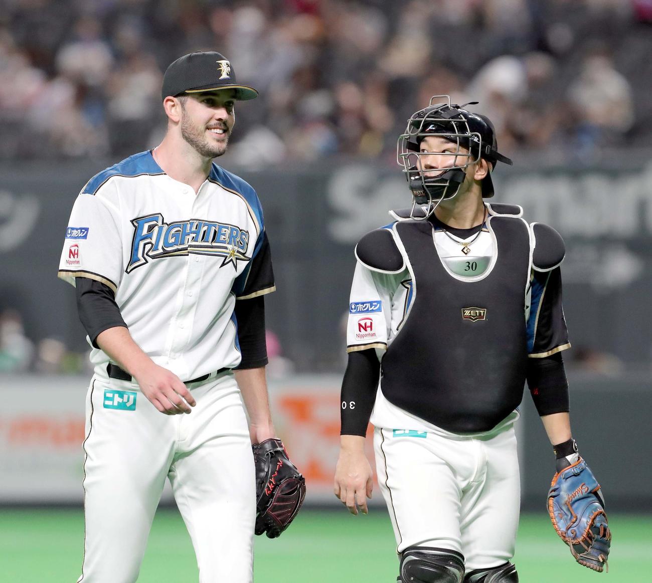 日本ハム対オリックス　5回表を無失点に抑え笑顔でベンチに戻る日本ハム・バーヘイゲンと宇佐見（右）（撮影・佐藤翔太）