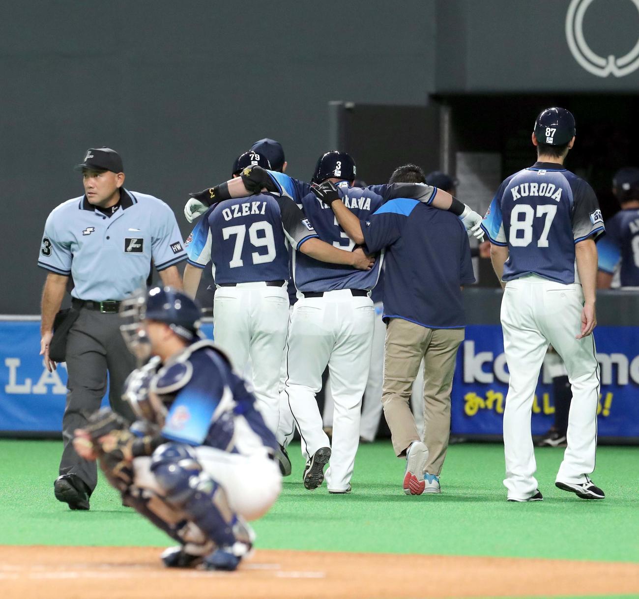 日本ハム対西武　1回表西武2死、三振後バランスを崩し右足を痛めた山川はスタッフらに付き添われながらベンチに戻る（撮影・佐藤翔太）