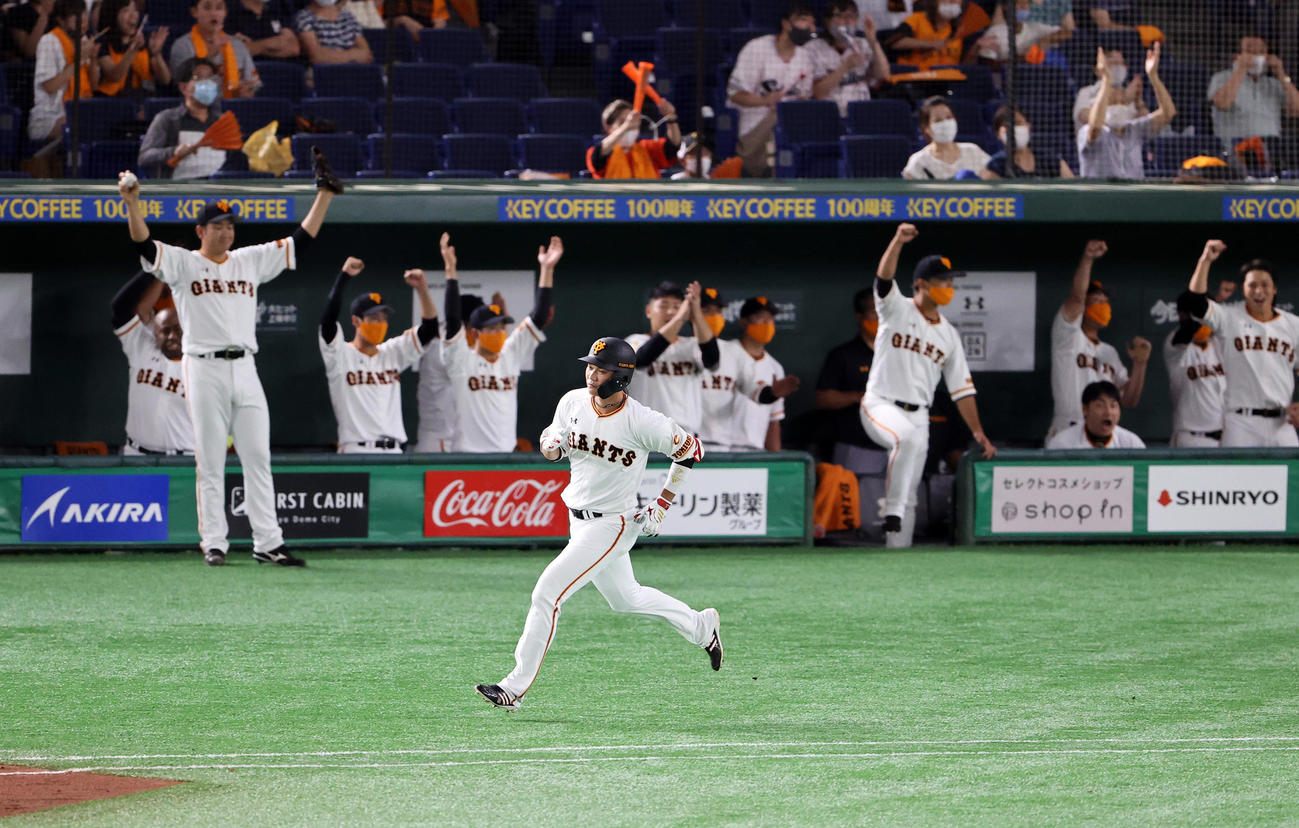 巨人対ヤクルト　2回裏巨人2死二塁、坂本は左翼2点本塁打を放ち、バンザイして喜ぶ菅野（左奥）ら喜ぶ巨人ベンチを背に一塁を回る（撮影・浅見桂子）