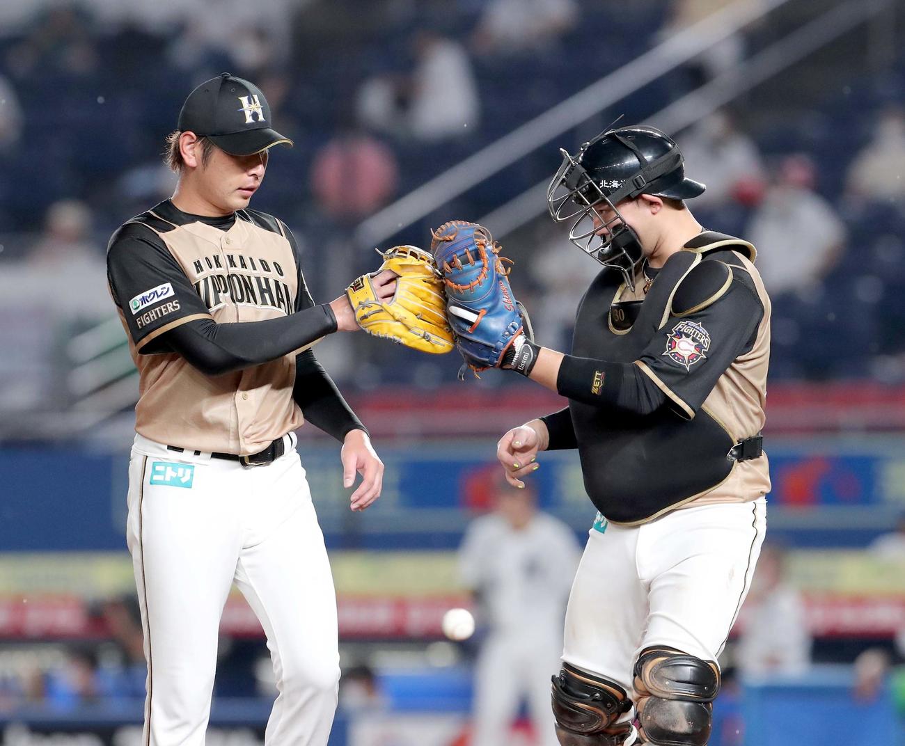 ロッテ対日本ハム　3回裏を無失点に抑えグラブタッチを交わしながらベンチに戻る日本ハム加藤と宇佐見（右）（撮影・佐藤翔太）