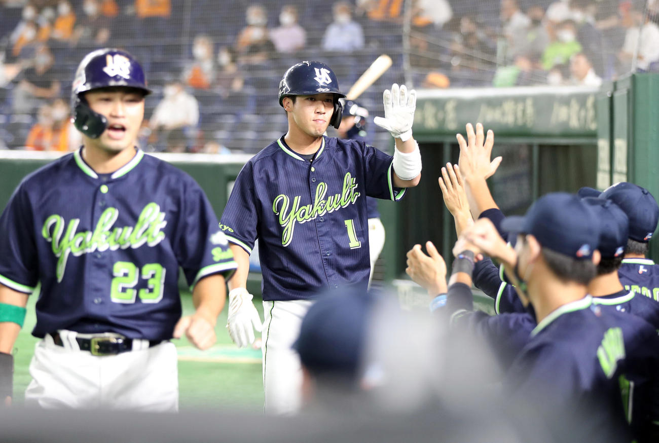 巨人対ヤクルト　1回表ヤクルト1死二、三塁、西浦の2点適時二塁打で生還し、ベンチに迎えられる山田哲（中央）。手前は青木（撮影・狩俣裕三）