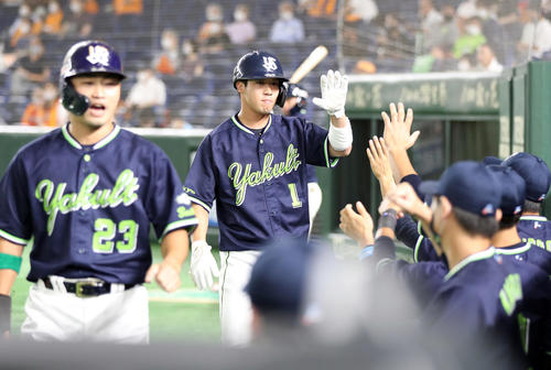巨人対ヤクルト　1回表ヤクルト1死二、三塁、西浦の2点適時二塁打で生還し、ベンチに迎えられる山田哲（中央）。手前は青木（撮影・狩俣裕三）