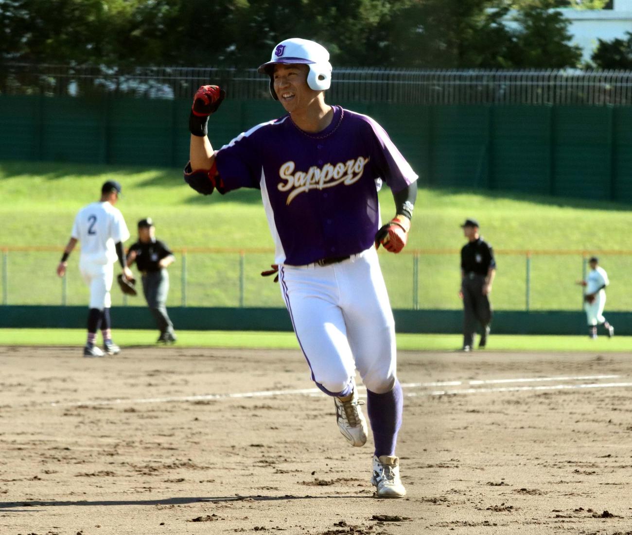 札幌大対北翔大　1回表札幌大2死二塁、公式戦1号となる右越え2ランを放ち笑顔で右手を挙げる大坂（撮影・永野高輔）