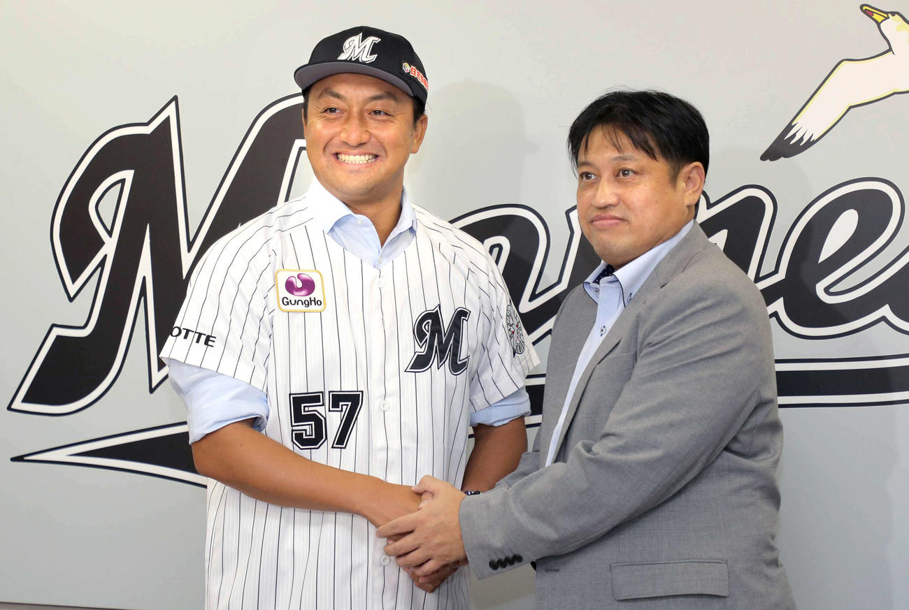 松本球団本部長（右）と笑顔で握手する沢村（代表撮影）
