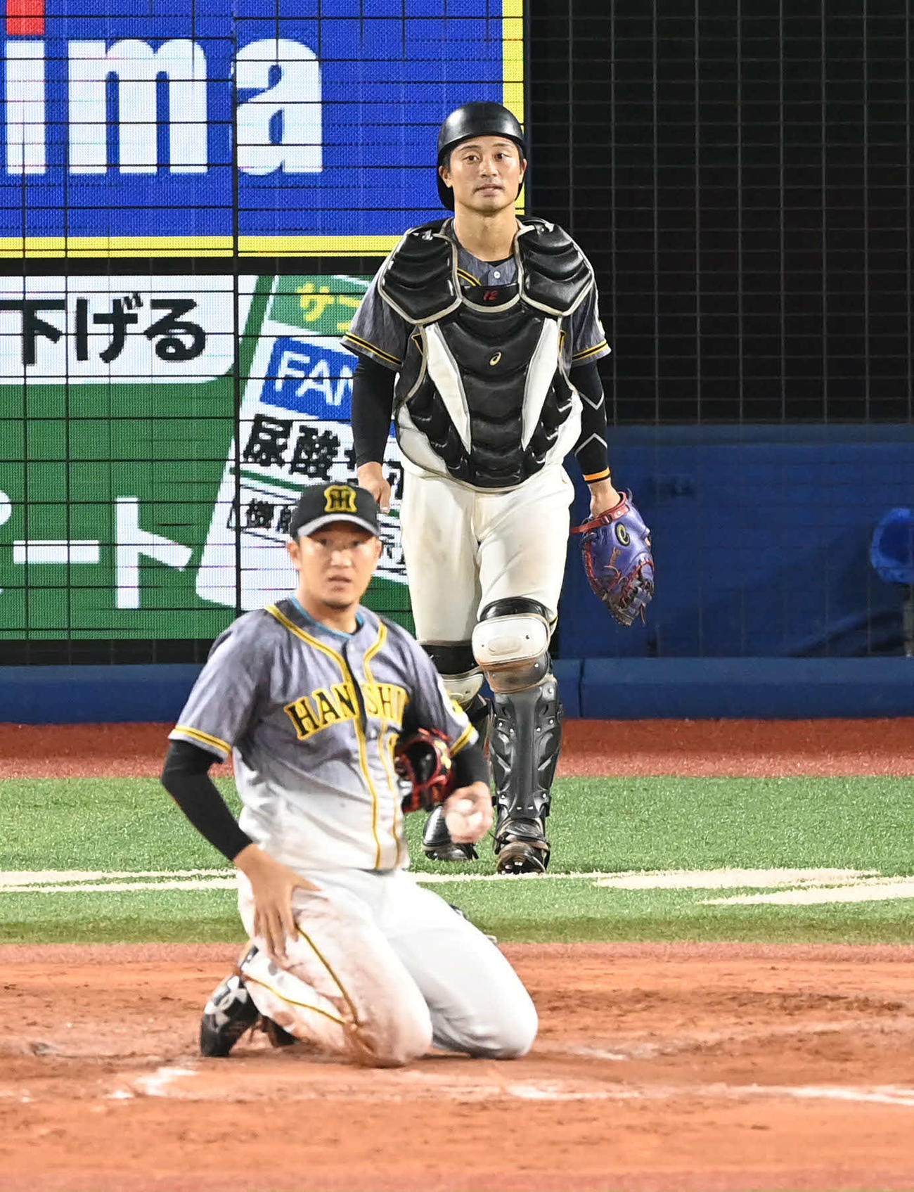 DeNA対阪神　6回裏DeNA1死満塁、坂本（後方）は岩貞の投球を捕逸。三塁走者倉本を生還させる（撮影・山崎安昭）