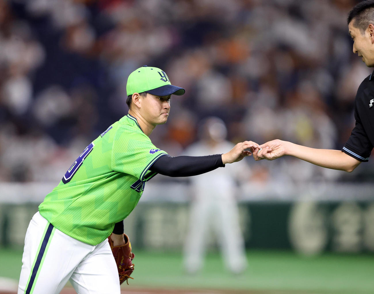 巨人対ヤクルト　2回裏、ユニホームのロゴを隠すシールがはがれ、球審に手渡す吉田喜（撮影・狩俣裕三）