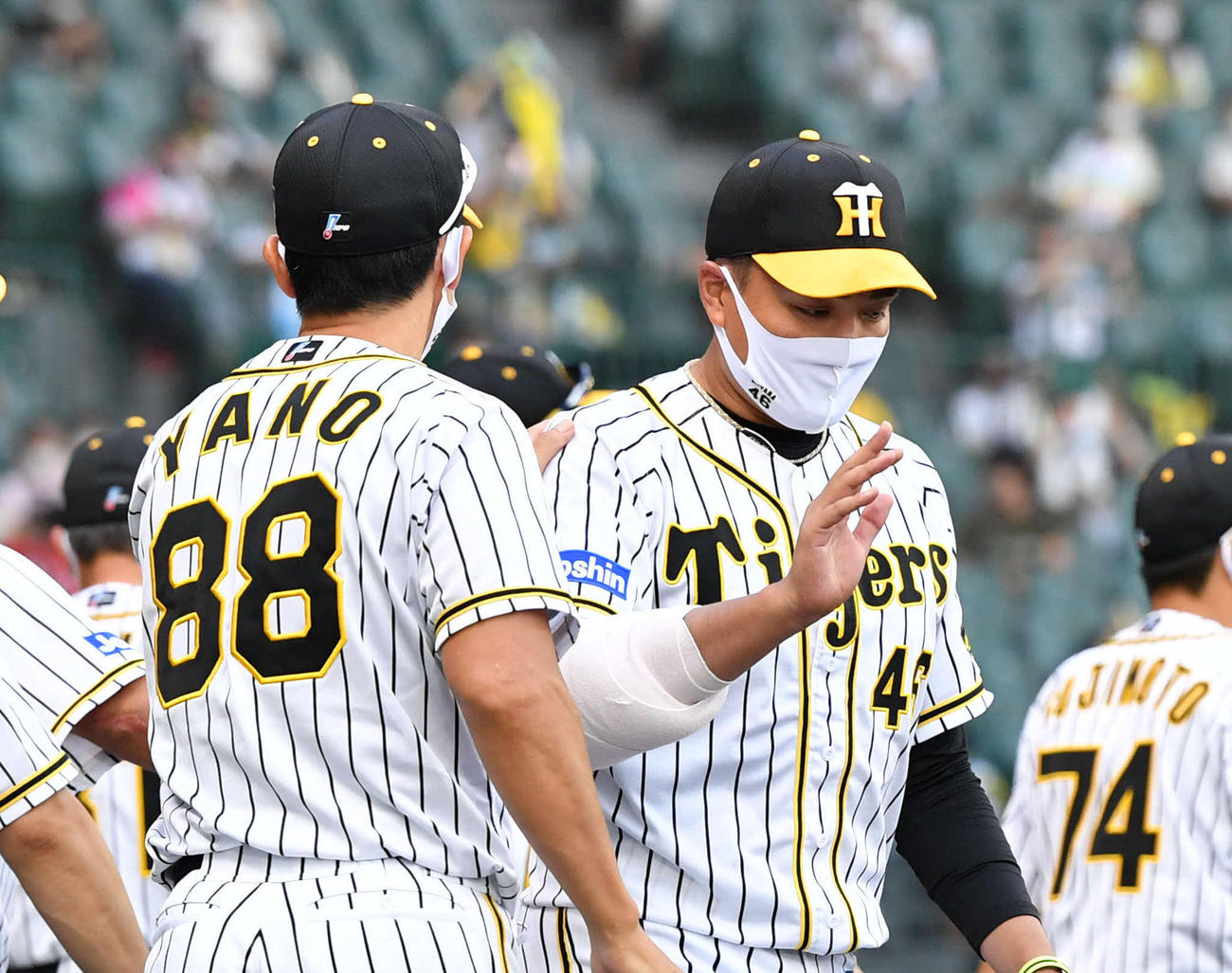 8回途中1失点で5勝目を挙げた秋山拓巳（右）は矢野監督から肩を叩かれる（撮影・岩下翔太）
