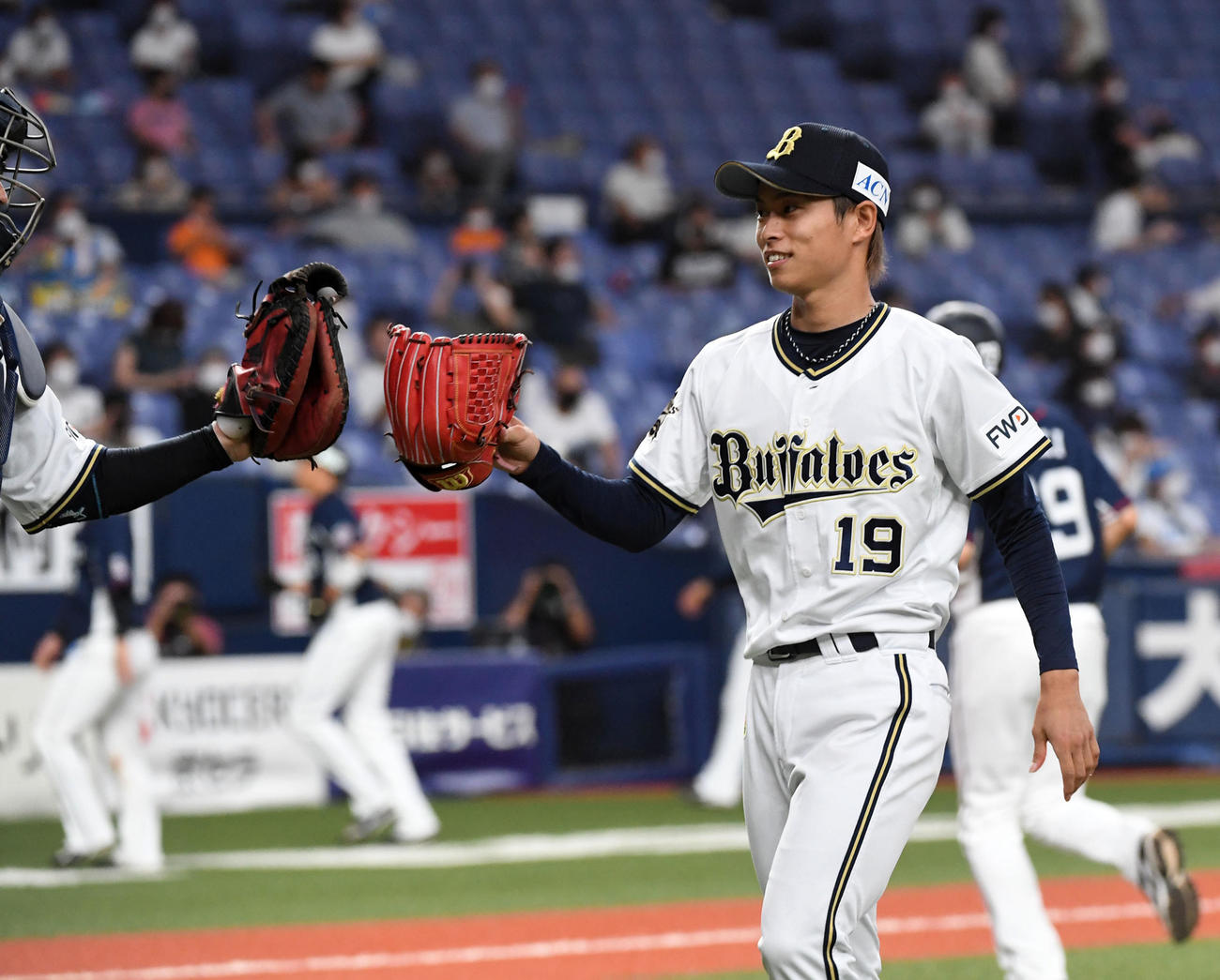 オリックス対西武　6回、ベンチに戻る山岡（右）は若月と笑顔でグラブタッチ（撮影・前岡正明）