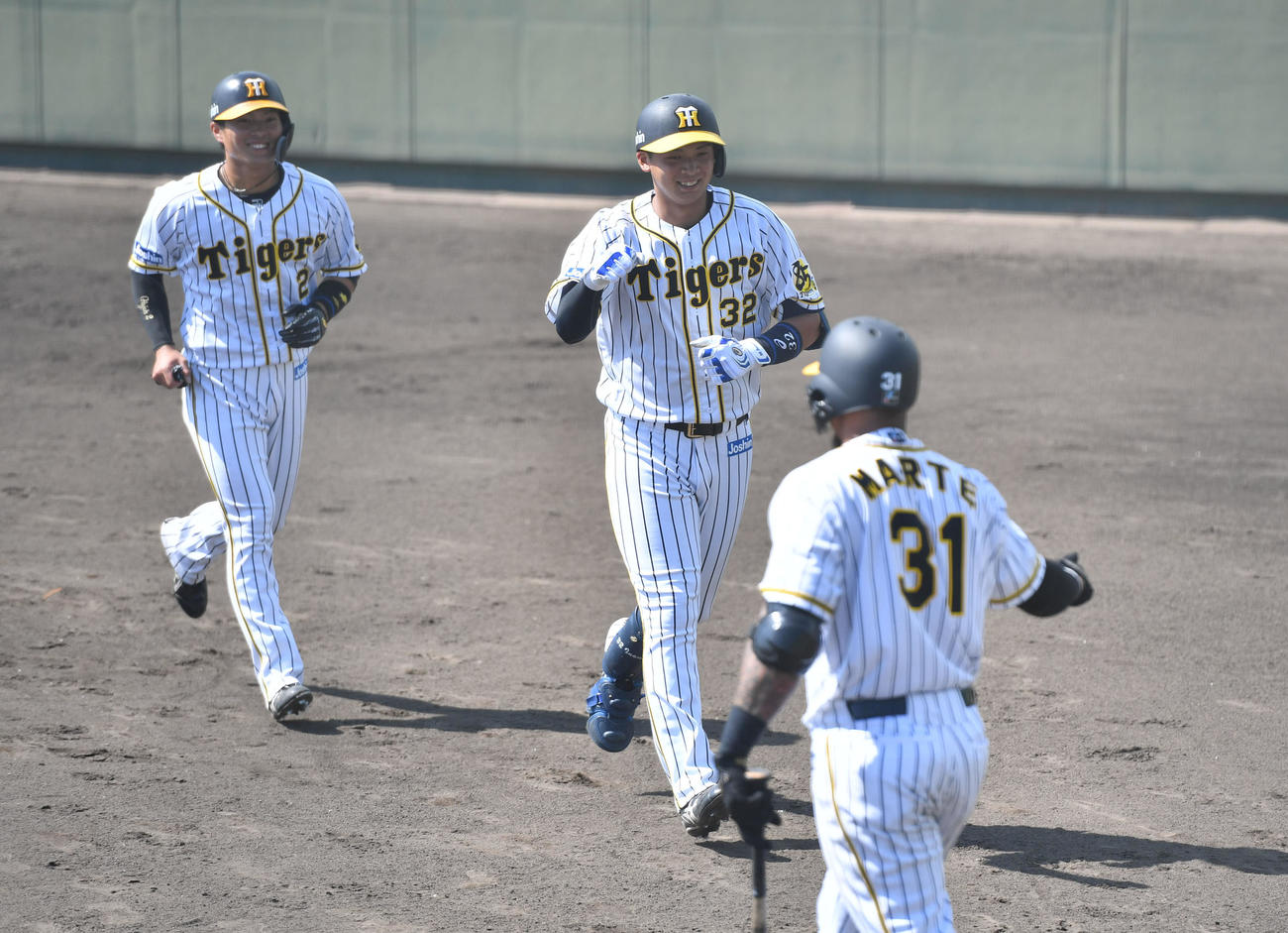 ウエスタン・リーグ阪神対中日　3回裏阪神1死一塁、井上（中央）は左中間へ2点本塁打を放ち、マルテ（右）とエアタッチ。左は北條（撮影・岩下翔太）