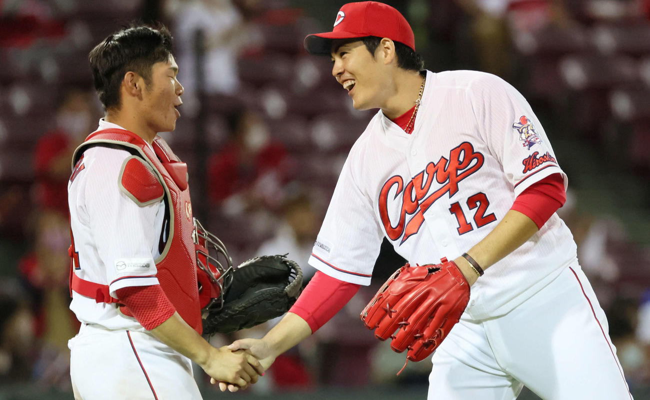 完封勝利を挙げた九里（右）は坂倉と笑顔で握手を交わす（撮影・加藤孝規）