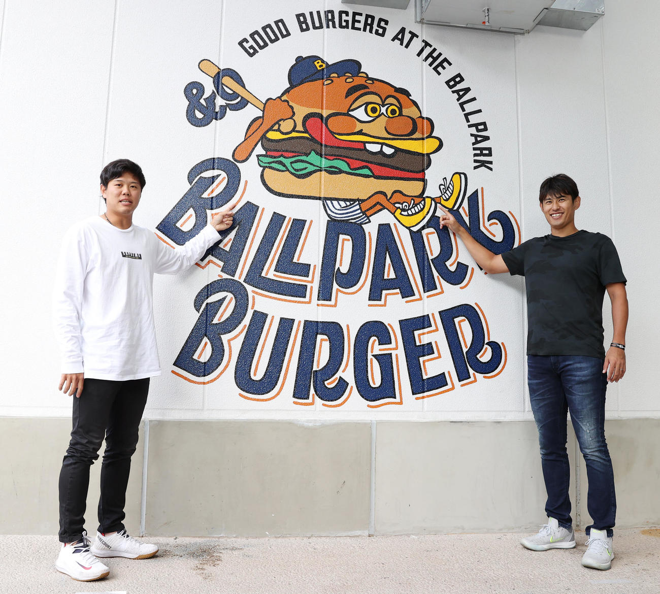 横浜スタジアム新店舗「BALLPARK　BURGER　＆9」プレス向け内覧会に出席したDeNA上茶谷（左）と井納は店のロゴの前で記念写真に納まる（撮影・垰建太）