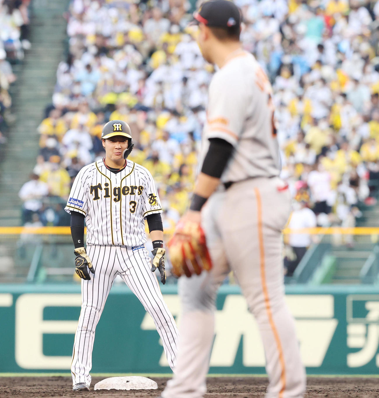 阪神対巨人　5回裏阪神1死一、二塁、ボーアの四球で二塁に進んだ大山は三塁手岡本（手前）と見合せ笑みを浮かべる＝（撮影・垰建太）