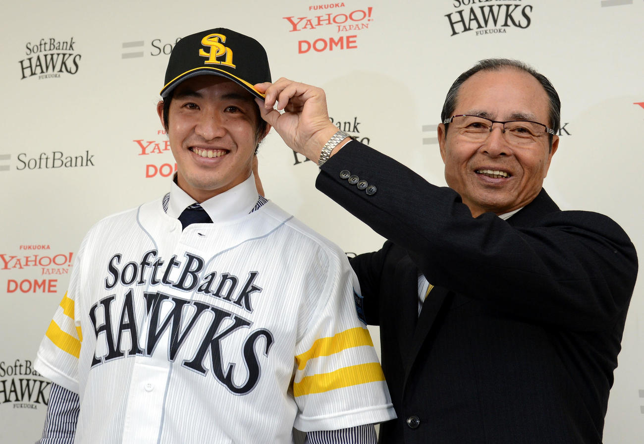 12年11月、ユニホームに袖を通し王会長から帽子をかぶせてもらう五十嵐