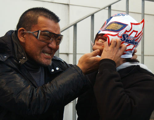 08年12月、「良い体してるなあ。何者だ？」と、プロレスラー蝶野正洋（左）からマスクへ手を掛けられ懸命に抵抗するスワローズマン（五十嵐）