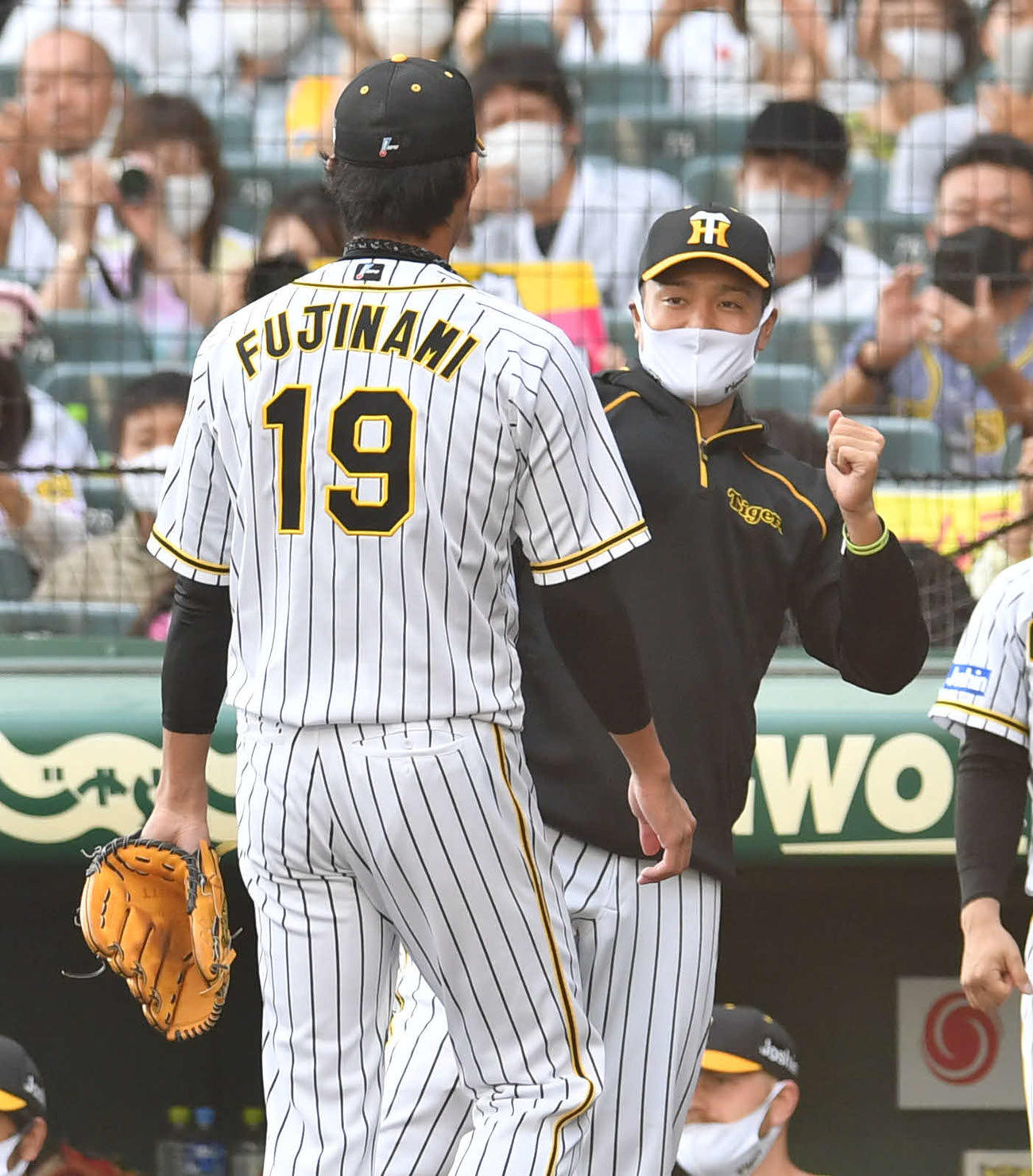 三者凡退に抑えた藤浪晋太郎（左）を迎える秋山拓巳（撮影・岩下翔太）