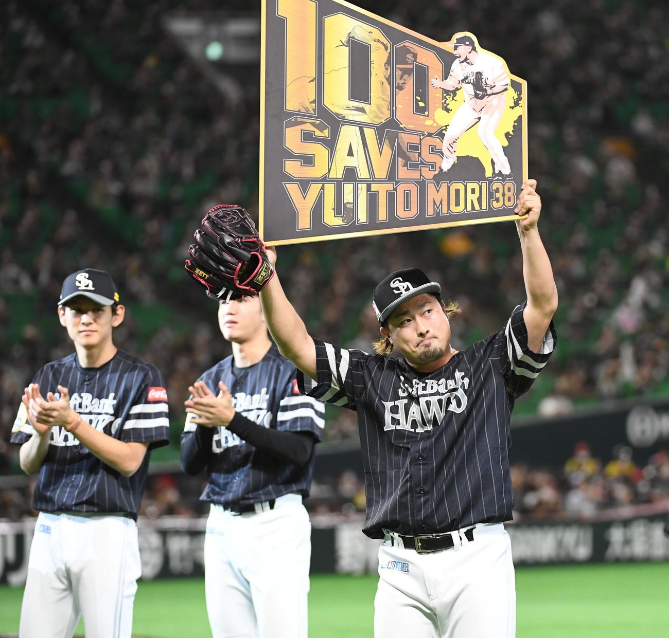 9回を抑え100セーブを挙げた森唯斗は記念のボードを持ち上げる（撮影・今浪浩三）