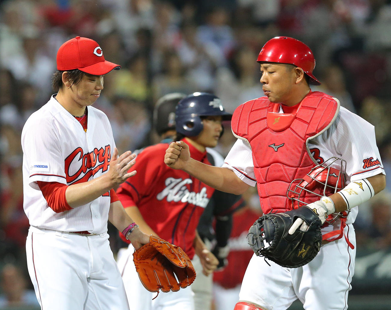 14年5月、交流戦で前田健（左）とタッチする石原慶幸