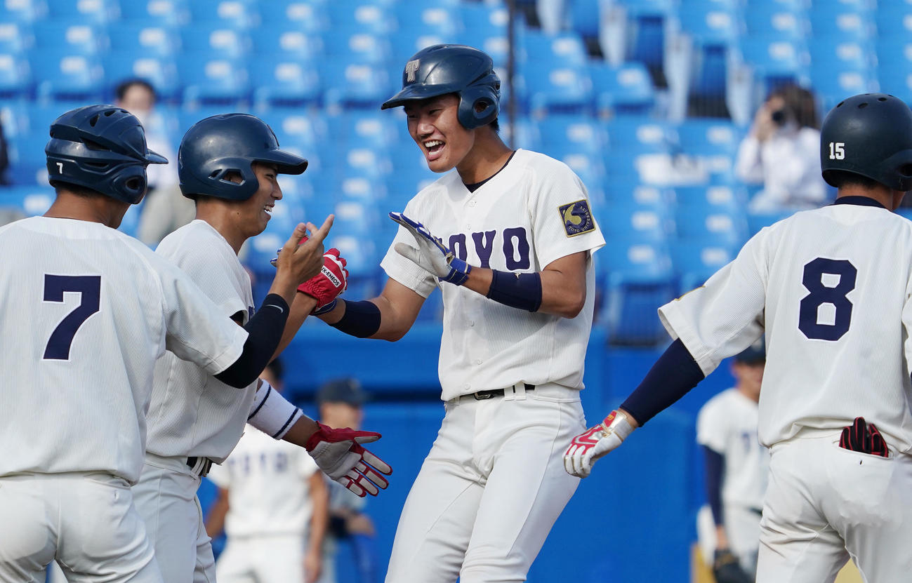 東洋大対中大　1回表東洋大1死一、三塁、左越えに3点本塁打を放ち、ナインに迎えられる東洋大・小口（中央）（撮影・菅敏）